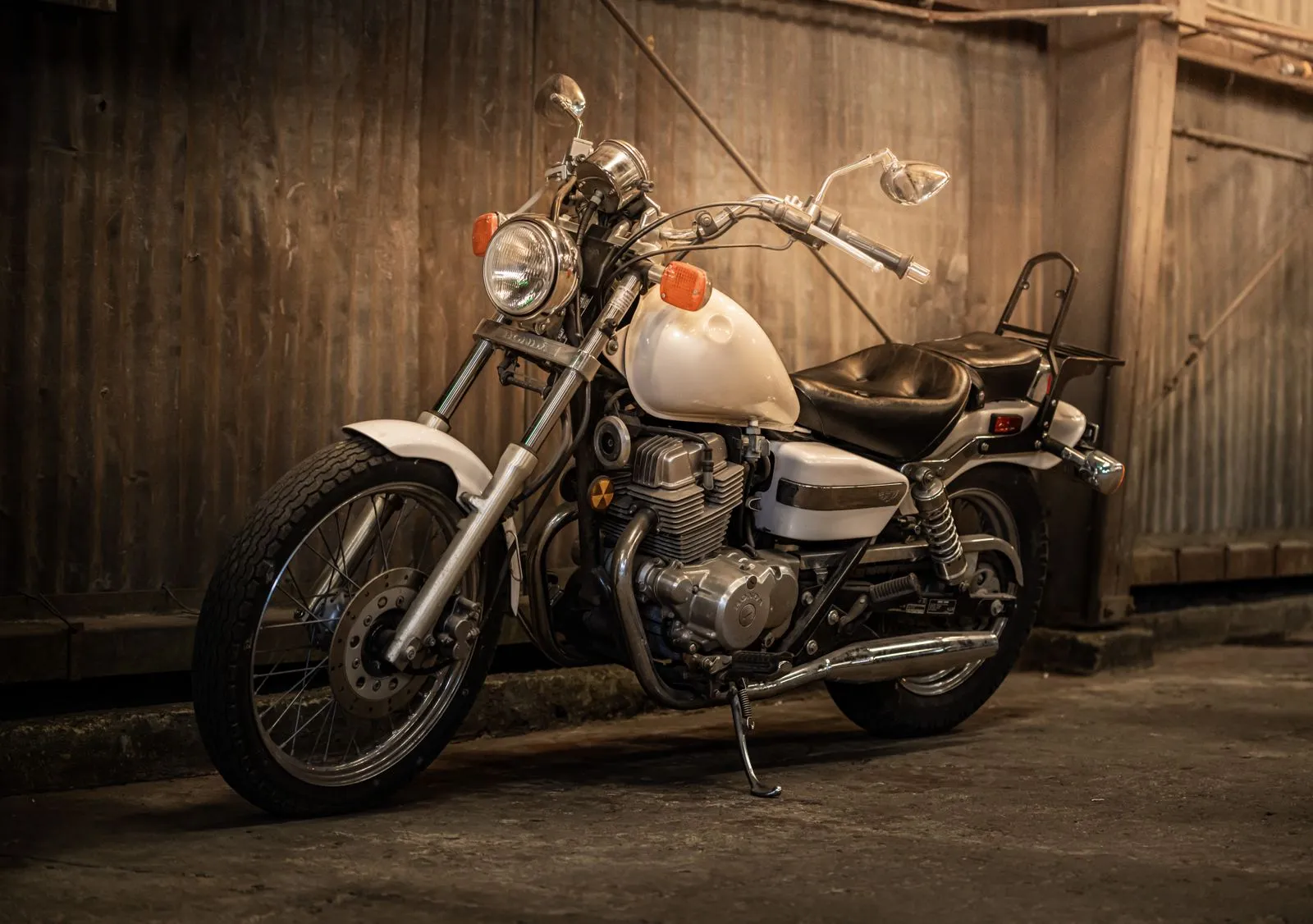 Classic vintage motorcycle parked indoors against a rustic wall, showcasing its timeless design and details.